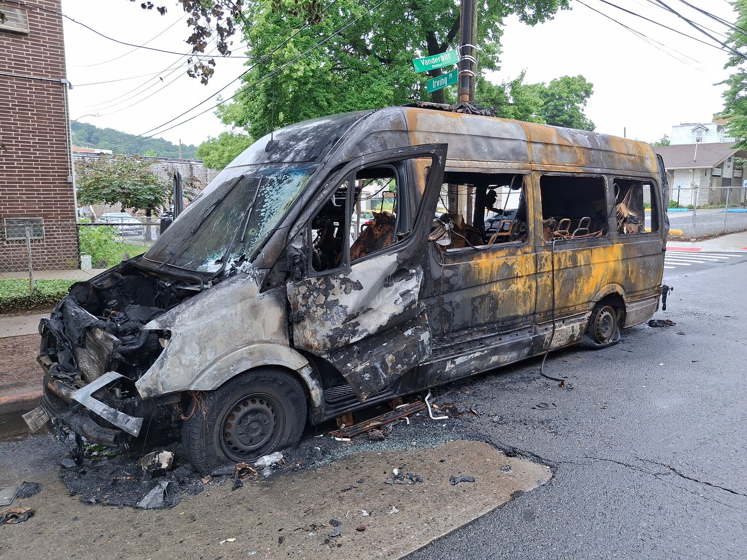 Image shows charred van at side of street at Staten Island intersection